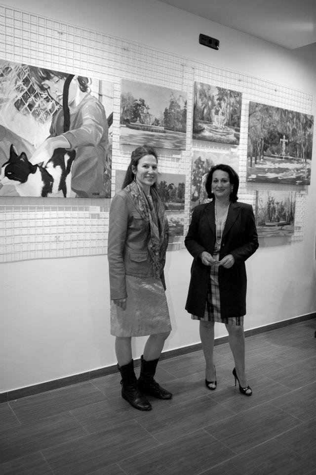 Two young woman at their painting exhibition in front of paintings