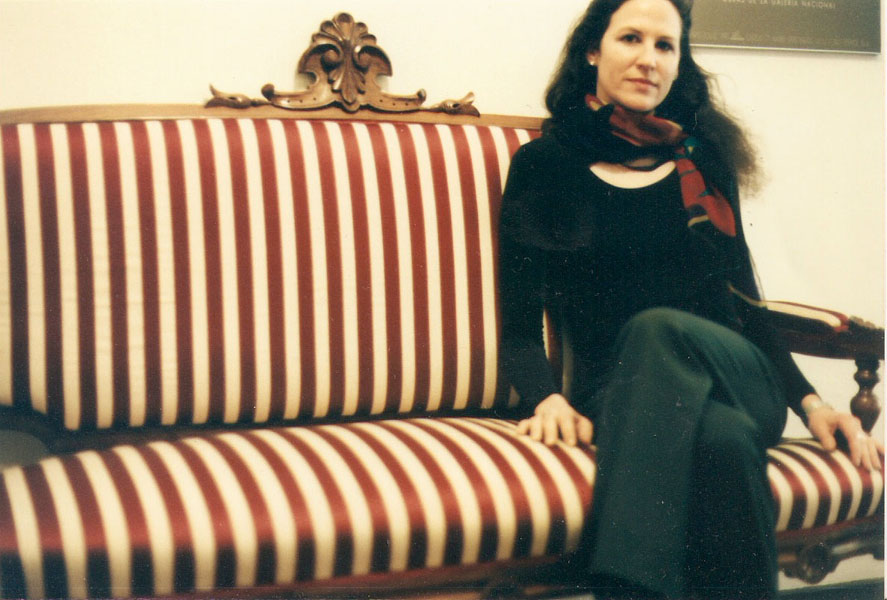 Young woman sitting on striped couch.