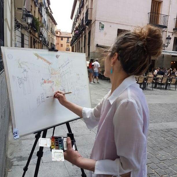 A photo of a woman painting a street in Madrid on site.