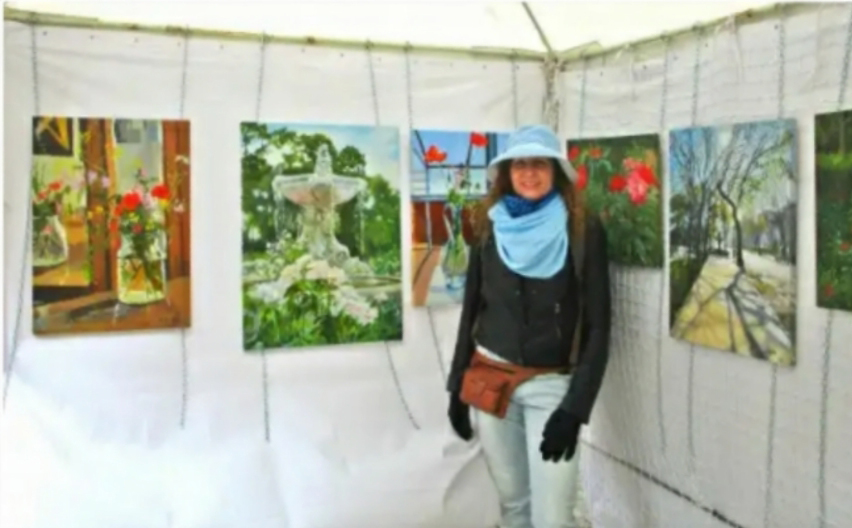 Art stand with female artist with blue hat and blue scarf.