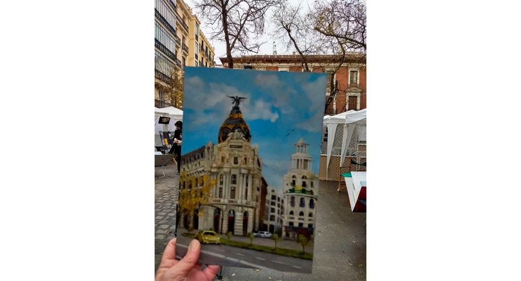 This is a small oil painting on a wood panel of the Metropolis Building of Madrid . It is held in my hand for size reference.